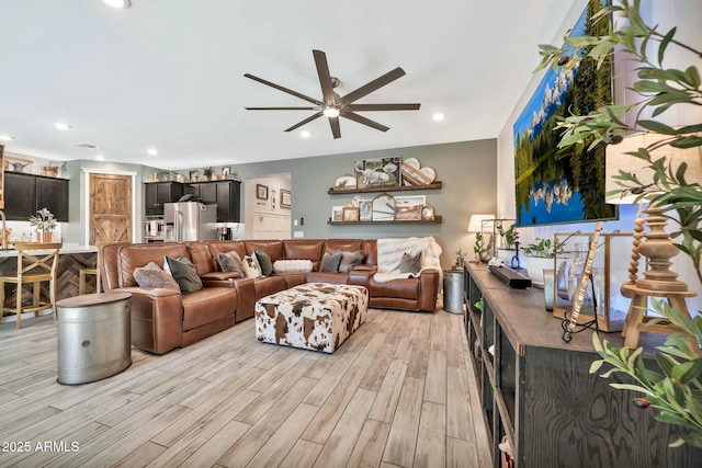 living room with ceiling fan, light hardwood / wood-style floors, and sink