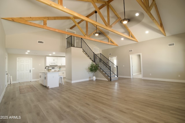 2573 E Superstition Blvd, Apache Junction, AZ 85119 - unfurnished living room featuring high vaulted ceiling, beam ceiling, a sink, stairs, and baseboards