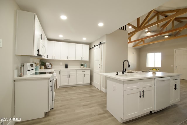 2573 E Superstition Blvd, Apache Junction, AZ 85119 - kitchen featuring white appliances, a sink, a barn door, an island with sink, and white cabinetry