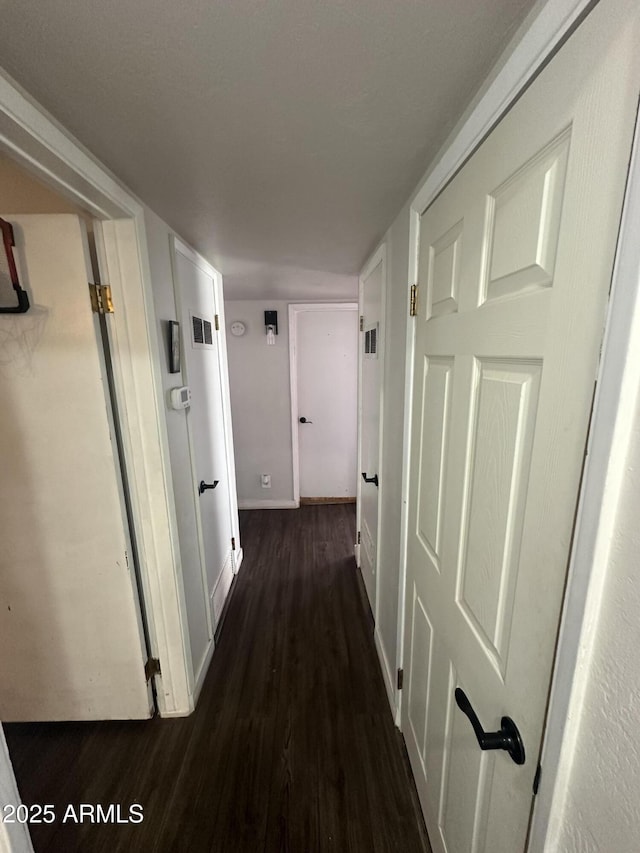 hallway featuring baseboards and dark wood finished floors