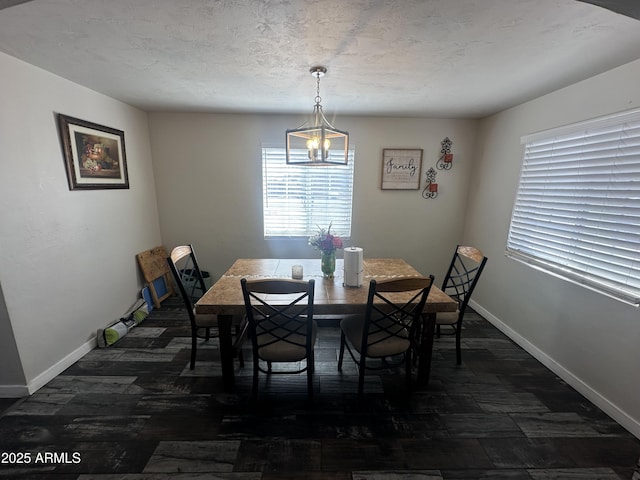 dining space featuring a notable chandelier, a textured ceiling, dark wood-style floors, and baseboards