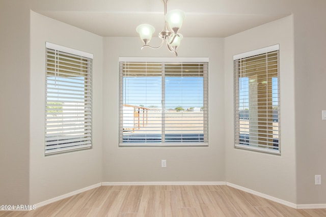 unfurnished room with hardwood / wood-style floors and a notable chandelier