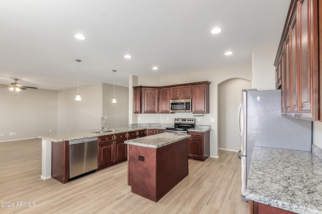 kitchen with ceiling fan, sink, pendant lighting, a kitchen island, and appliances with stainless steel finishes