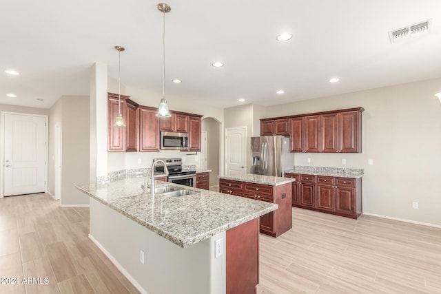 kitchen with sink, hanging light fixtures, light hardwood / wood-style flooring, kitchen peninsula, and stainless steel appliances