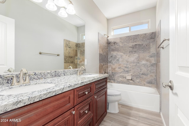 full bathroom featuring vanity, hardwood / wood-style floors, tiled shower / bath combo, and toilet