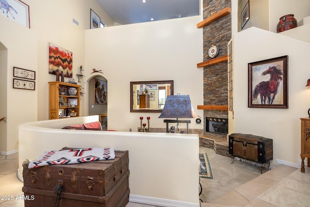 tiled living room with a high ceiling and a stone fireplace