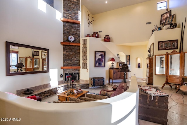 living room with a high ceiling, a healthy amount of sunlight, and a stone fireplace