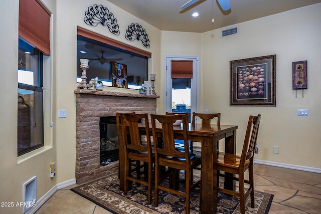 dining area with ceiling fan and a fireplace