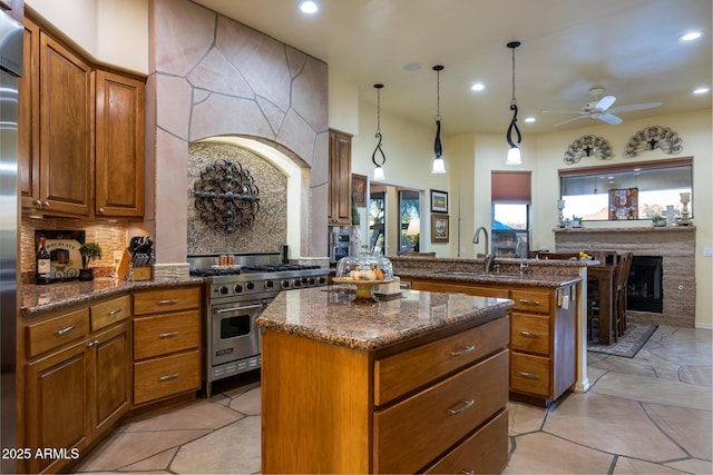 kitchen with luxury range, decorative light fixtures, a kitchen island, ceiling fan, and sink