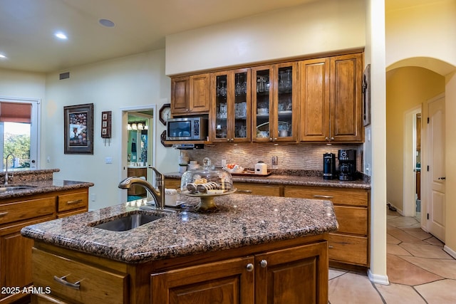 kitchen featuring stainless steel microwave, a center island with sink, and sink