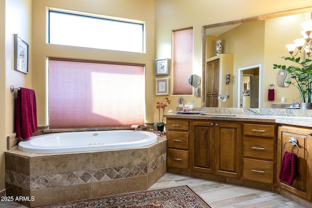 bathroom featuring a relaxing tiled tub and vanity