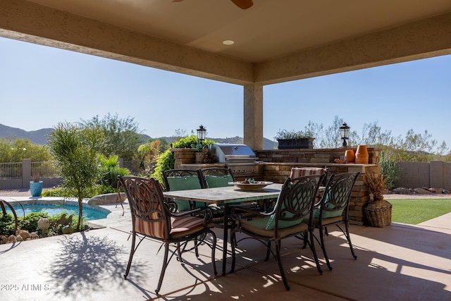 view of patio / terrace with an outdoor kitchen, a mountain view, a fenced in pool, area for grilling, and ceiling fan