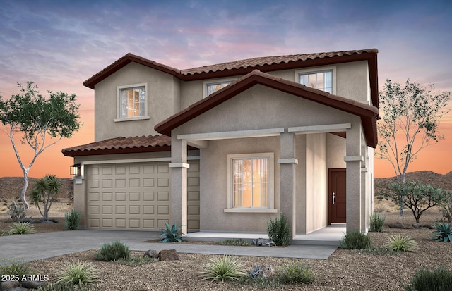 mediterranean / spanish home with an attached garage, driveway, a tile roof, and stucco siding