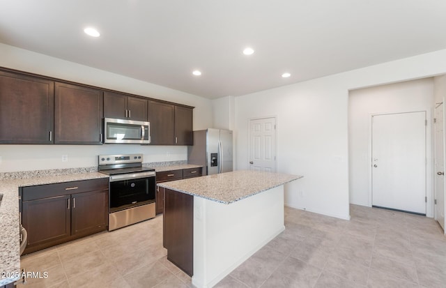 kitchen with recessed lighting, light stone counters, stainless steel appliances, and a center island