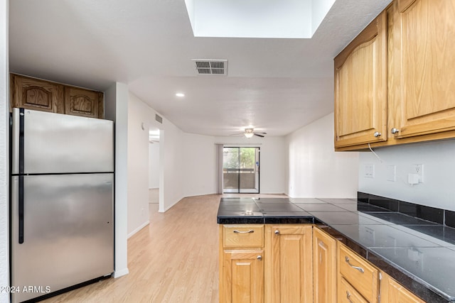 kitchen with ceiling fan, light wood-type flooring, and stainless steel refrigerator