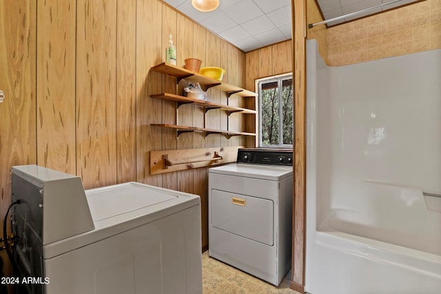 laundry room with separate washer and dryer and wood walls