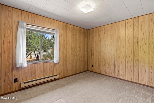 carpeted spare room with a baseboard heating unit and wood walls