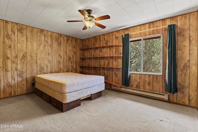 unfurnished bedroom with wooden walls, a baseboard radiator, ceiling fan, and carpet flooring