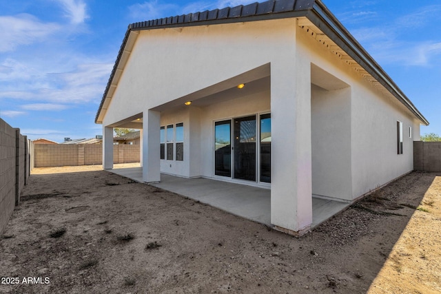 rear view of house featuring stucco siding, a patio, and a fenced backyard