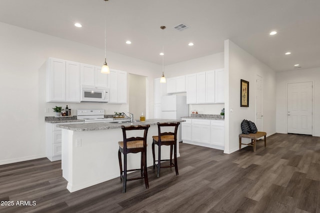 kitchen featuring visible vents, white appliances, white cabinetry, and a kitchen island with sink