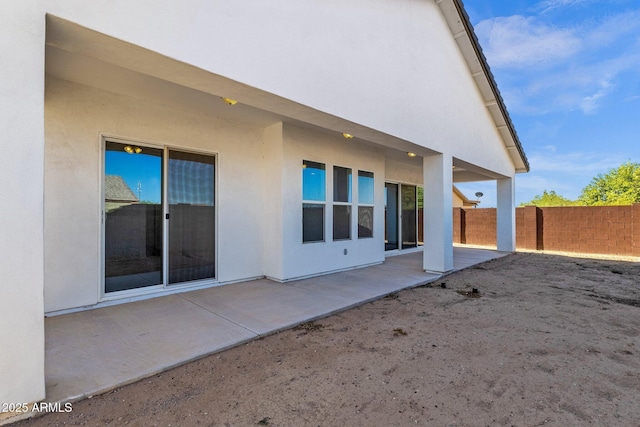 rear view of property with a patio area, fence, and stucco siding