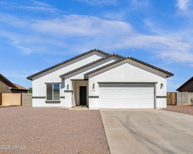 ranch-style home with concrete driveway, fence, a garage, and stucco siding