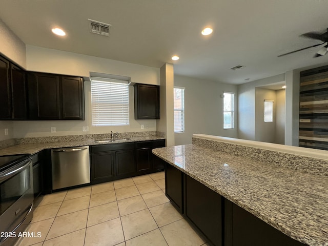 kitchen featuring stainless steel appliances, visible vents, a sink, and light stone countertops