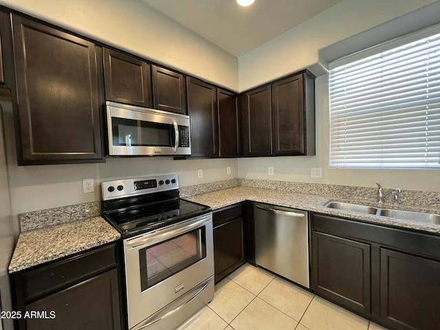 kitchen featuring light tile patterned floors, dark brown cabinetry, stainless steel appliances, a sink, and light countertops