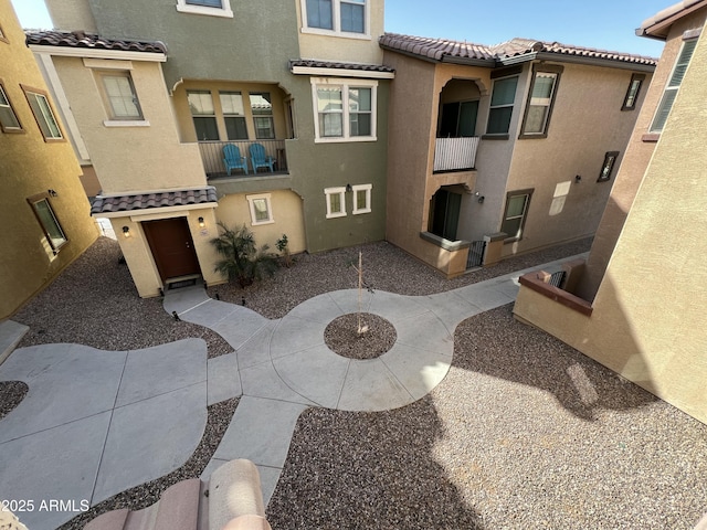 exterior space featuring a patio area, a tile roof, and stucco siding