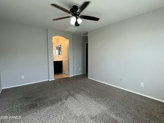 unfurnished bedroom with arched walkways, visible vents, carpet flooring, connected bathroom, and baseboards