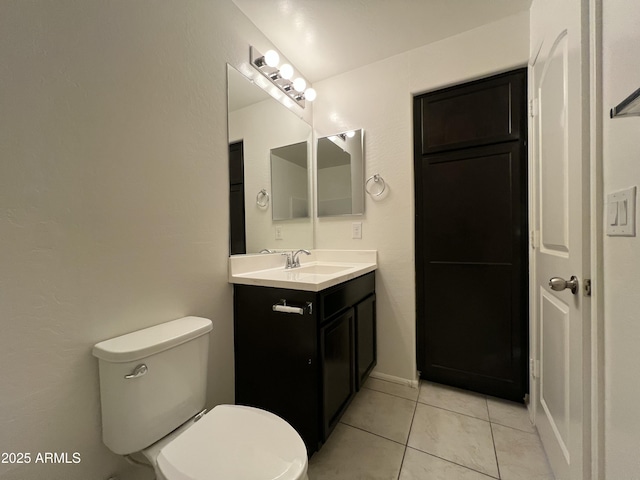 half bath featuring tile patterned flooring, vanity, and toilet