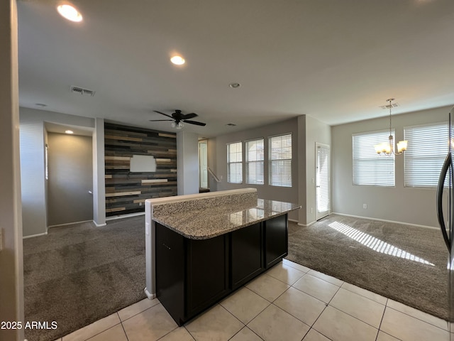 kitchen featuring light colored carpet, an accent wall, open floor plan, wooden walls, and light stone countertops