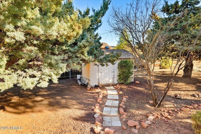 view of yard featuring a shed, fence, and an outdoor structure