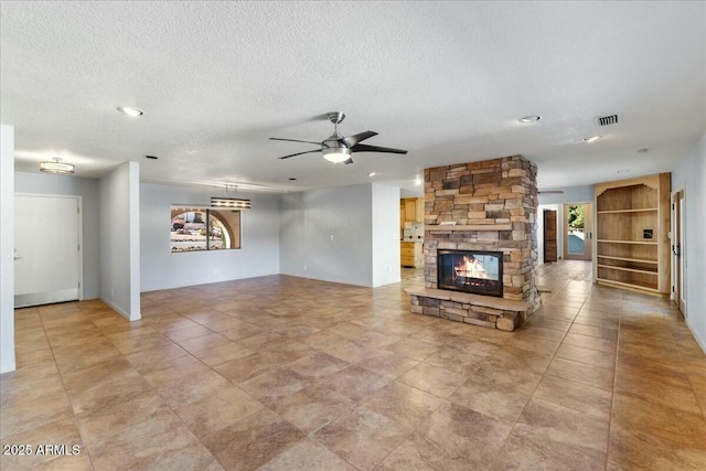 unfurnished living room with plenty of natural light, visible vents, a textured ceiling, and a stone fireplace