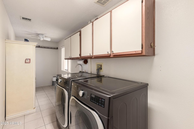 clothes washing area with visible vents, washing machine and clothes dryer, a ceiling fan, and cabinet space