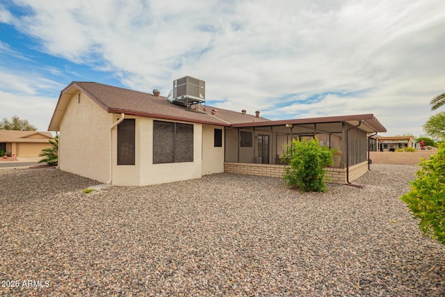 back of property featuring a sunroom, stucco siding, and central AC unit