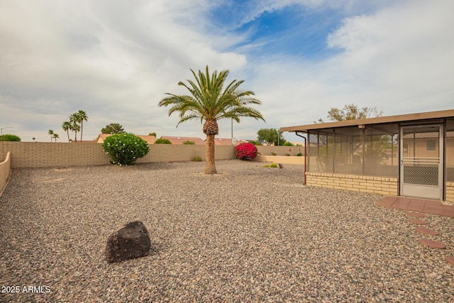 view of yard featuring a sunroom and a fenced backyard