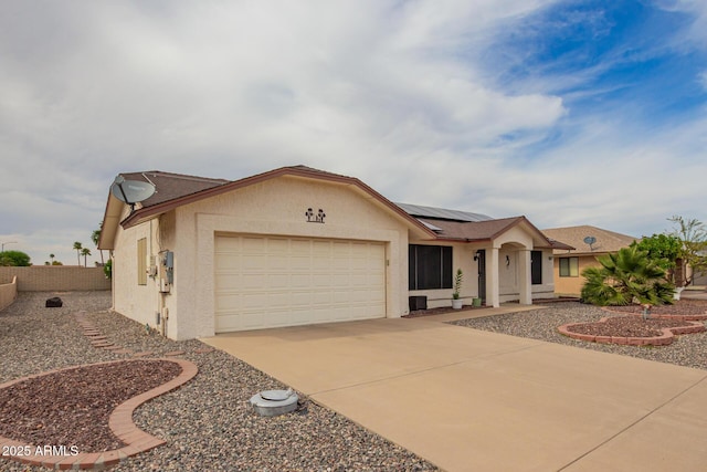 ranch-style home with roof mounted solar panels, a garage, fence, stucco siding, and driveway