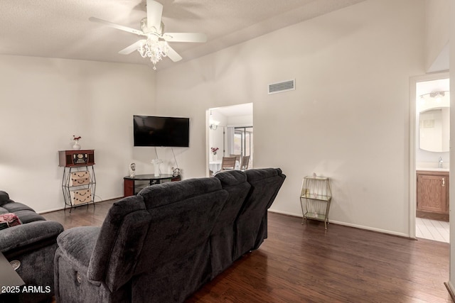 living area featuring a high ceiling, ceiling fan, dark wood-style floors, and visible vents