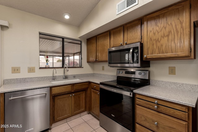 kitchen featuring light tile patterned floors, a textured ceiling, visible vents, appliances with stainless steel finishes, and a sink