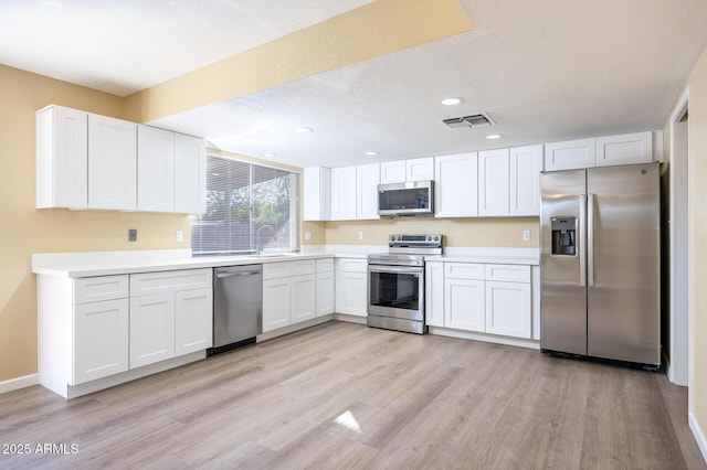 kitchen with white cabinetry, sink, light hardwood / wood-style flooring, a textured ceiling, and appliances with stainless steel finishes