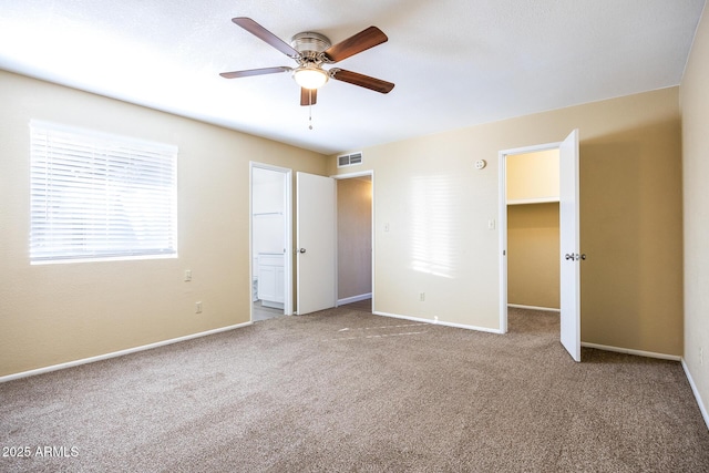 unfurnished bedroom featuring carpet, ceiling fan, a walk in closet, and a closet