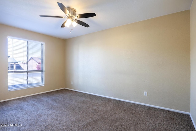 spare room featuring dark colored carpet and ceiling fan