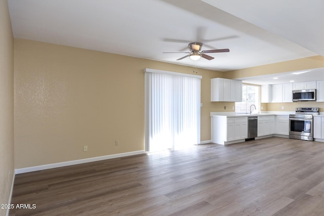 kitchen with white cabinets, stainless steel appliances, ceiling fan, and light hardwood / wood-style floors