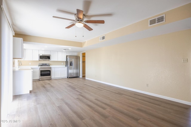 kitchen featuring sink, ceiling fan, appliances with stainless steel finishes, light hardwood / wood-style floors, and white cabinetry