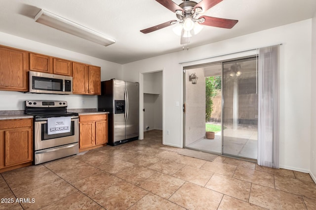 6085 S Wilson Dr, Chandler, AZ 85249 - kitchen featuring stainless steel appliances, brown cabinetry, a ceiling fan, and baseboards