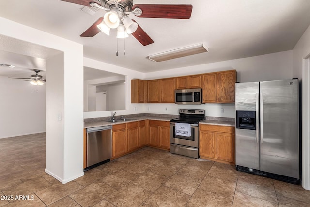 6085 S Wilson Dr, Chandler, AZ 85249 - kitchen with stainless steel appliances, ceiling fan, a sink, brown cabinetry, and baseboards