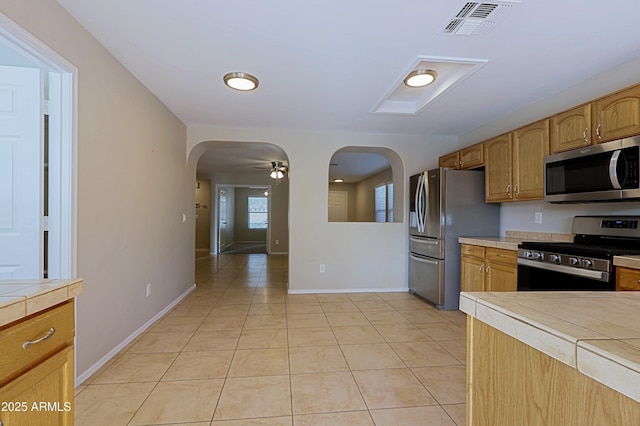 kitchen featuring tile countertops, ceiling fan, light tile patterned floors, and appliances with stainless steel finishes