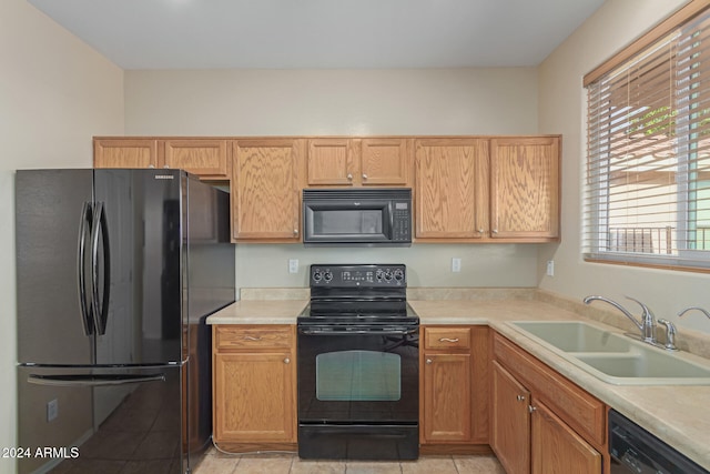 kitchen featuring sink, black appliances, and light tile patterned flooring