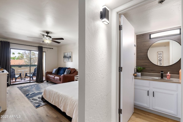 bedroom featuring ceiling fan, access to exterior, sink, and light wood-type flooring